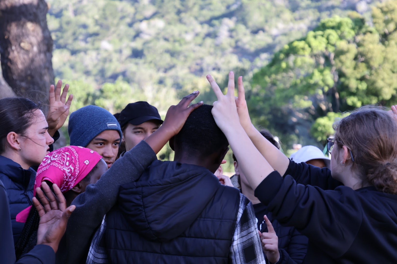 School learners in a group huddle with hands raised on an Outward Bound course at Wittedrift