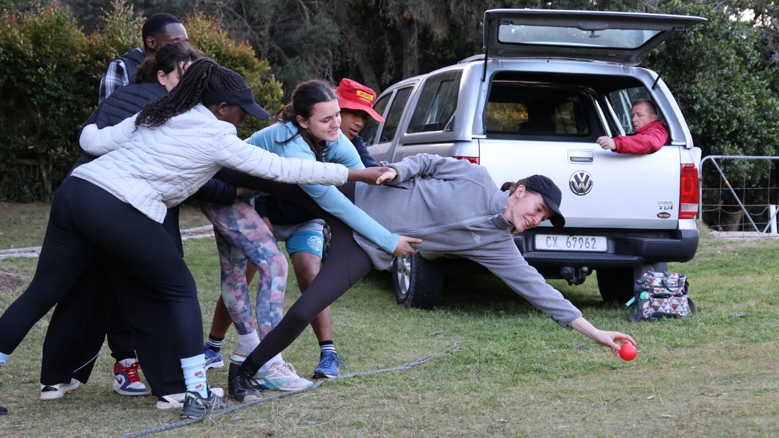 Students straining together to push a vehicle across the field in a teamwork challenge